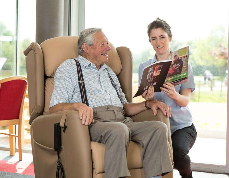 Healthcare Professional talking to elderly man in chair.