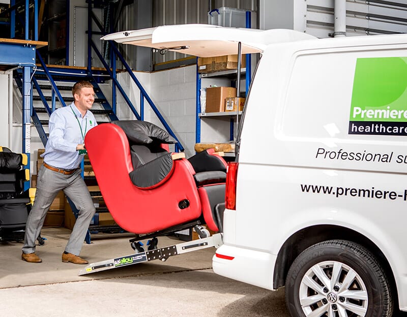 Man loading red chair into van. 