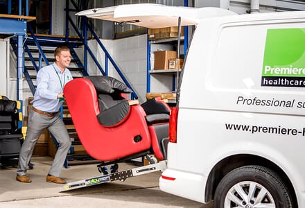 Man loading red chair into van. 
