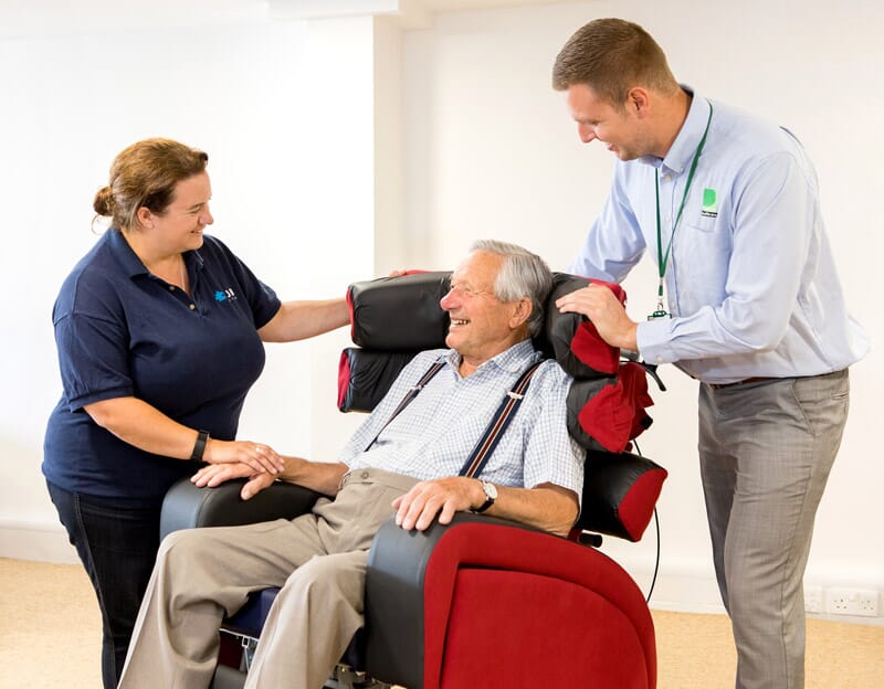Two Premiere Healthcare Employees assist man in red chair. 
