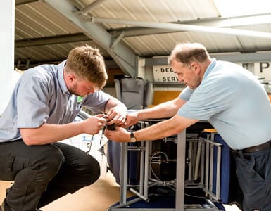 Two men fix chair frame.