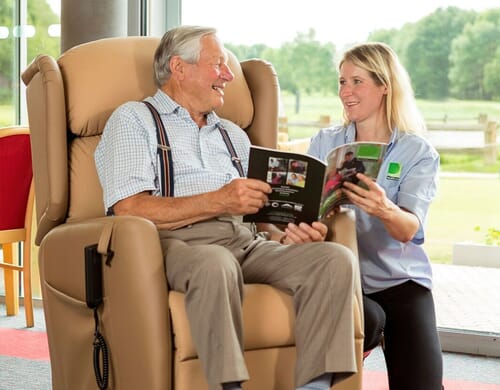 Healthcare Professional talking to elderly man in chair.