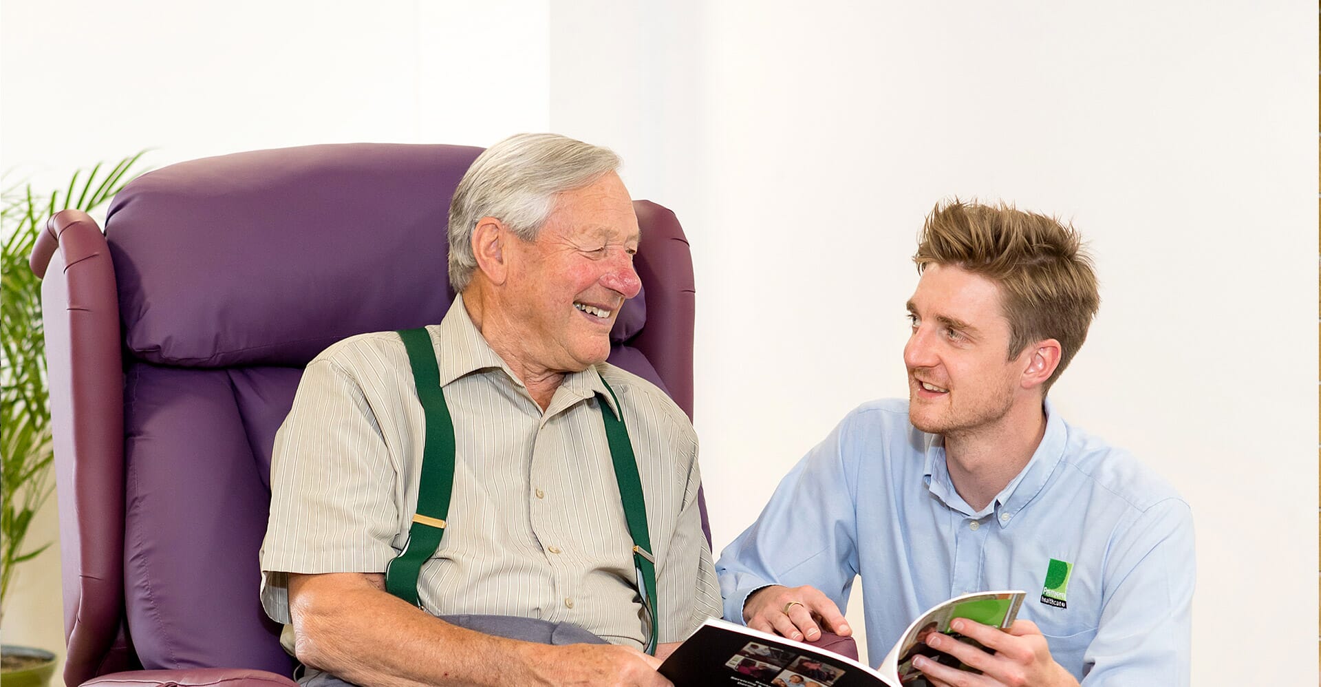 Healthcare Professional talking to elderly man in chair.