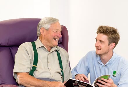 Healthcare Professional talking to elderly man in chair.
