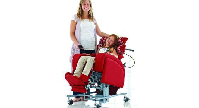 Women reclining  in red chair with helper.