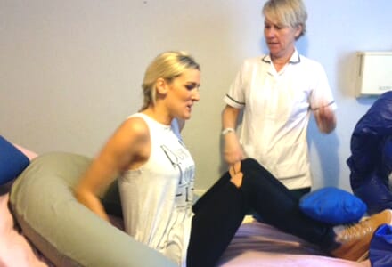 Healthcare Professional oversees Posture Management Training for Woman in Bed.