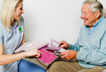 Healthcare Professional and Elderly Man Look at Fabric Samples.