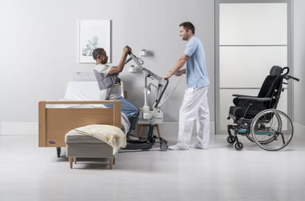 Care Assistant using Invacare Birdie EVO Compact Hoist Assisting Patient out of Chair.