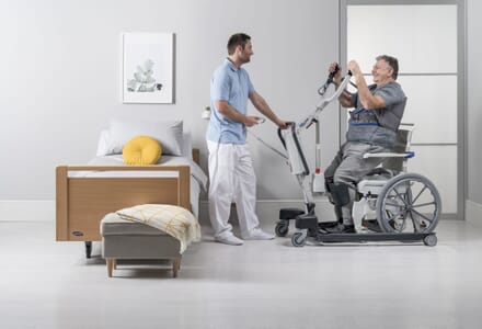 Care Assistant Helps Patient to Stand with Invacare ISA Compact patient lifter 